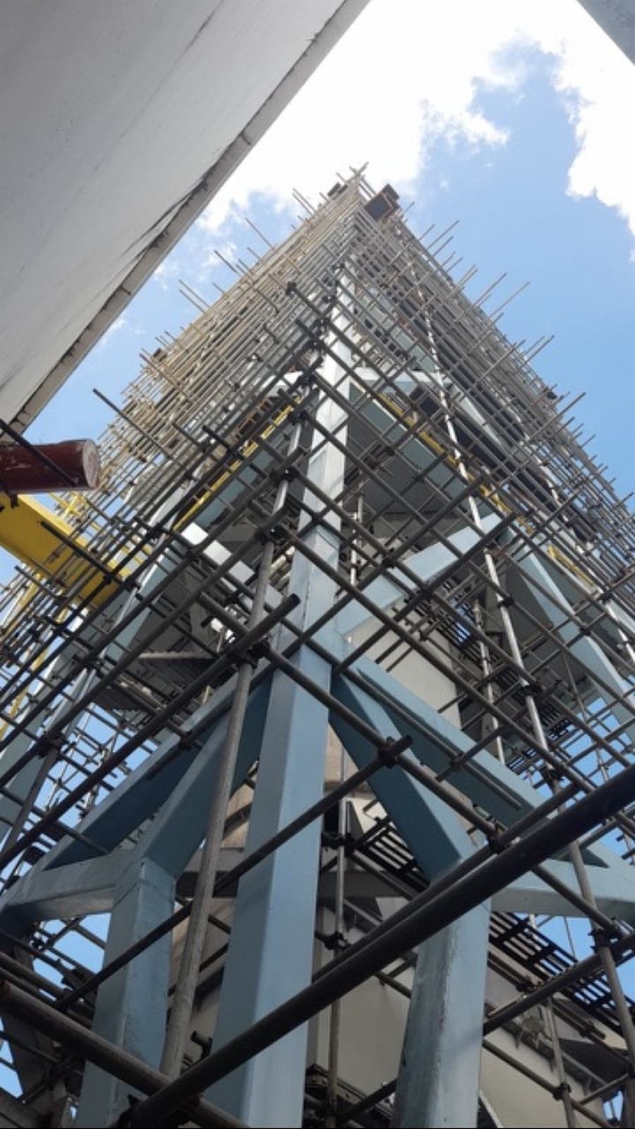 Scaffolding wrapped around a tall power plant smokestack
